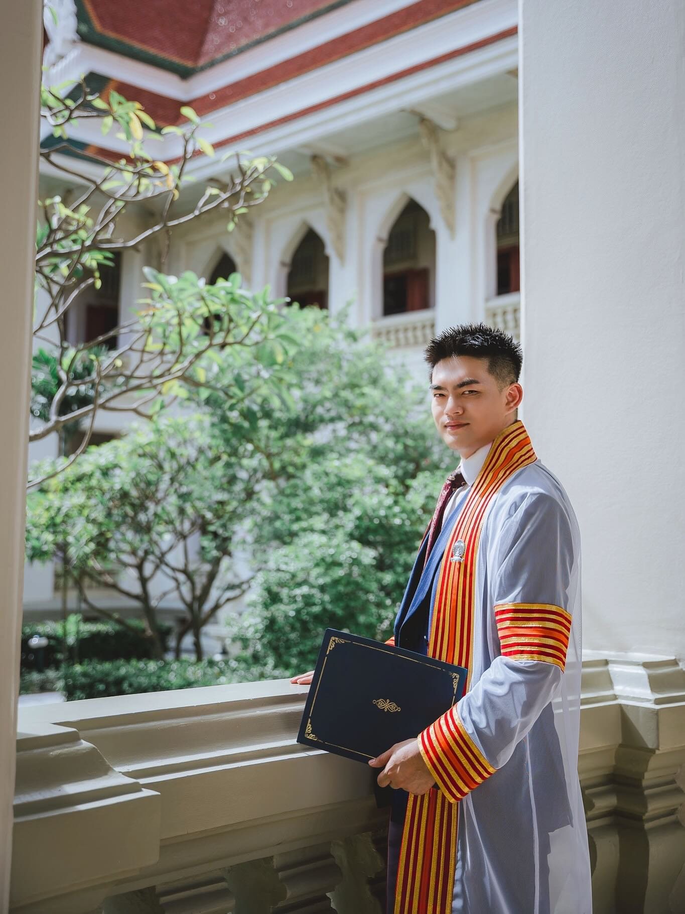 Dr. Chi Che at Chulalongkorn University, holding the doctoral folder